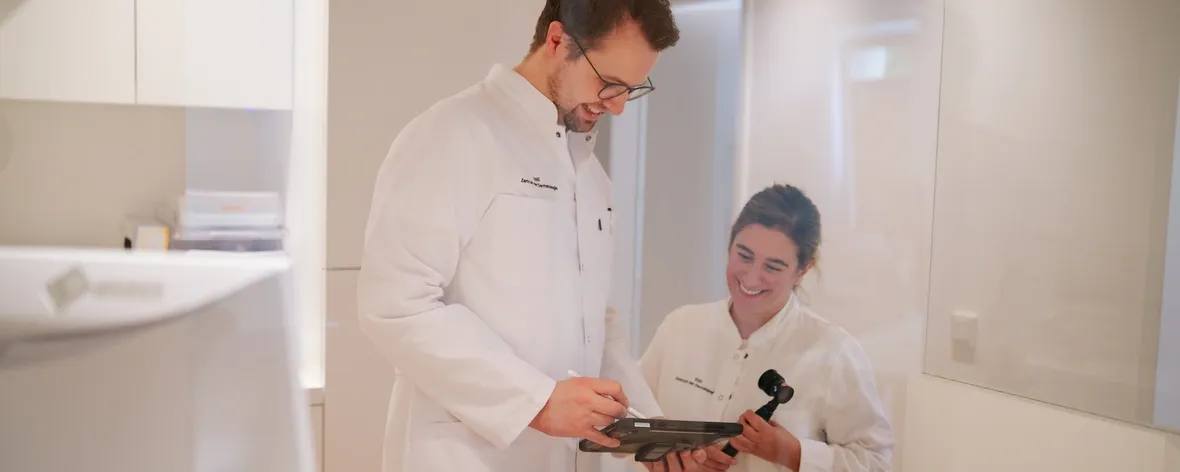 Foto von Dr. Jansen, der seiner Kollegin auf einem Tablet etwas erklärt